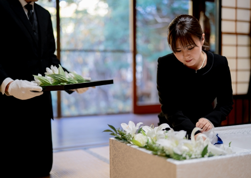 家族葬メモサが足立区で白い花を飾り直葬の棺に納棺準備をしている