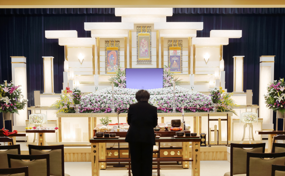 家族葬メモサが足立区で祭壇と花に囲まれた式場で事前相談を案内している